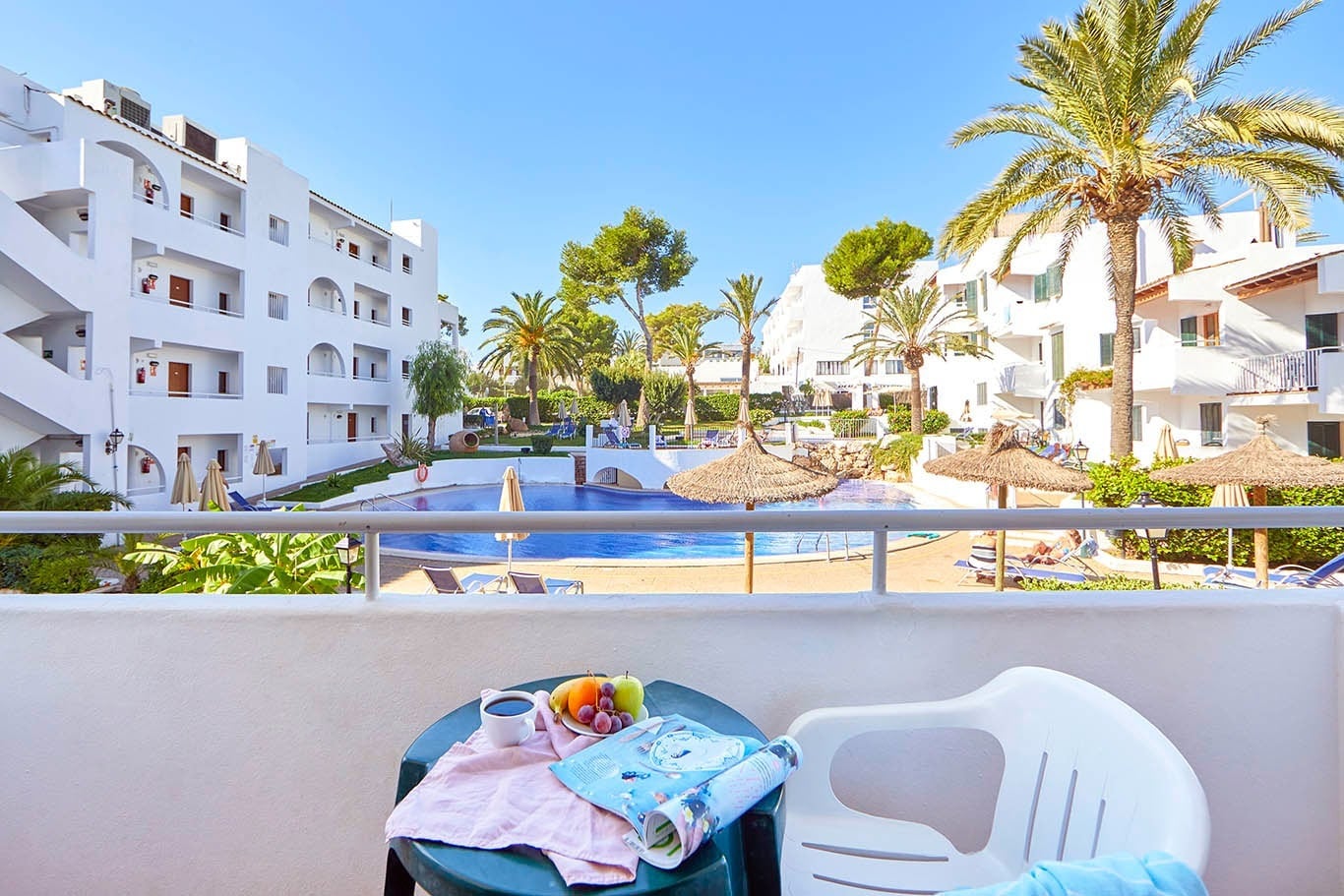 Vista al balcón, piscina y palmeras del hotel Gavimar Cala Gran Costa del Sur en Cala d'Or.