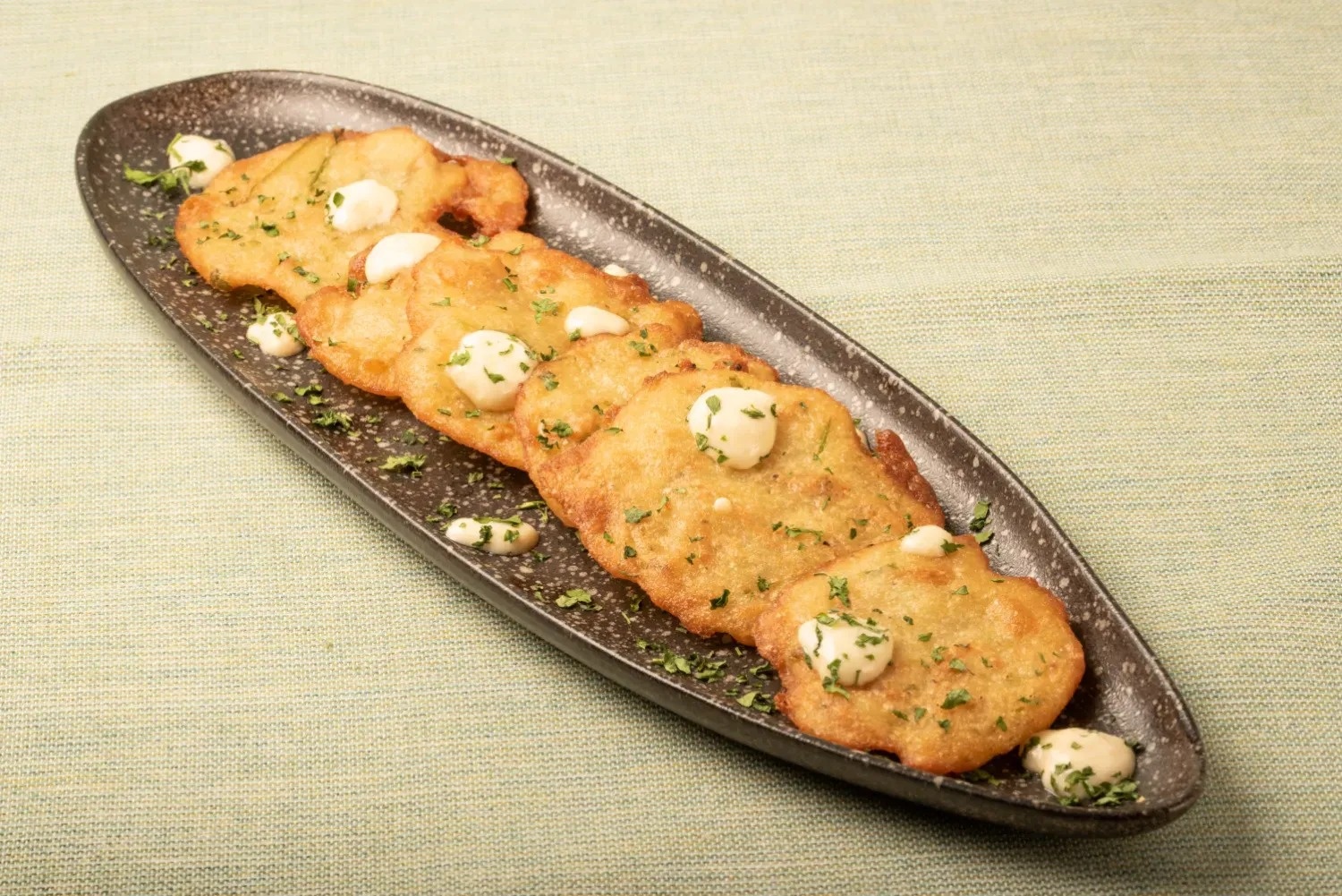 a black plate topped with fried potatoes and sauce