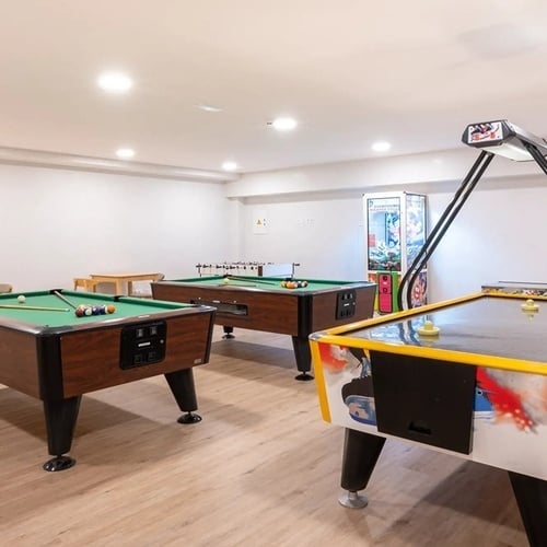 dos mesas de billar y una mesa de air hockey en una sala de juegos