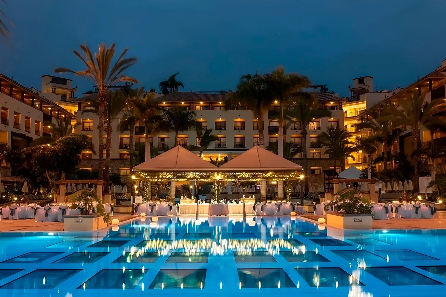 a bottle of wine sits on a table in front of a pool
