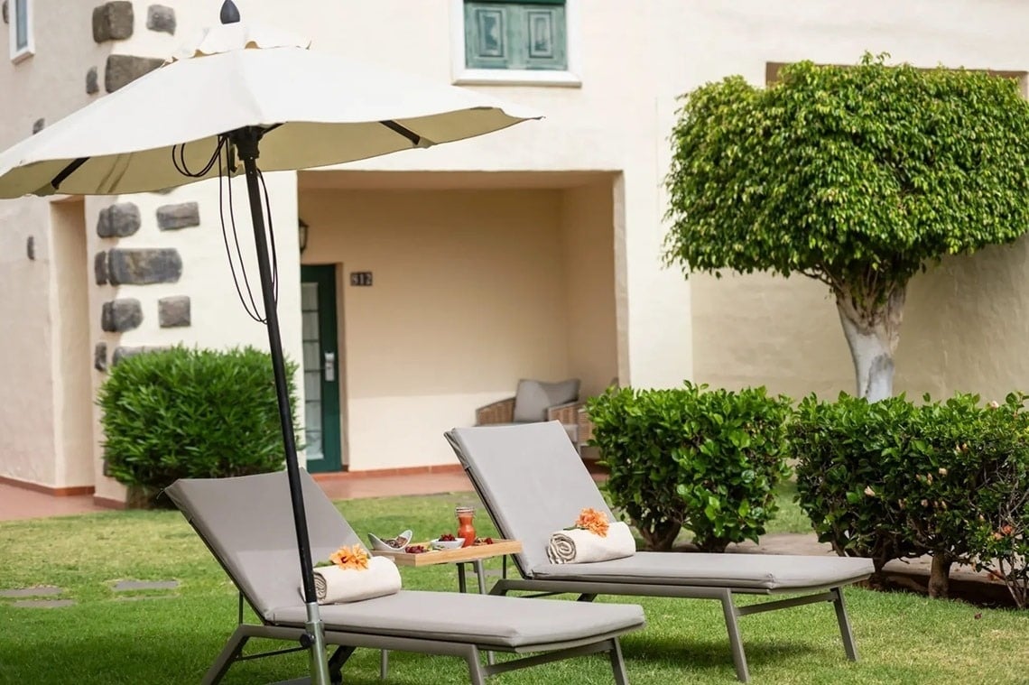 dos tumbonas y un paraguas en el césped frente a una casa
