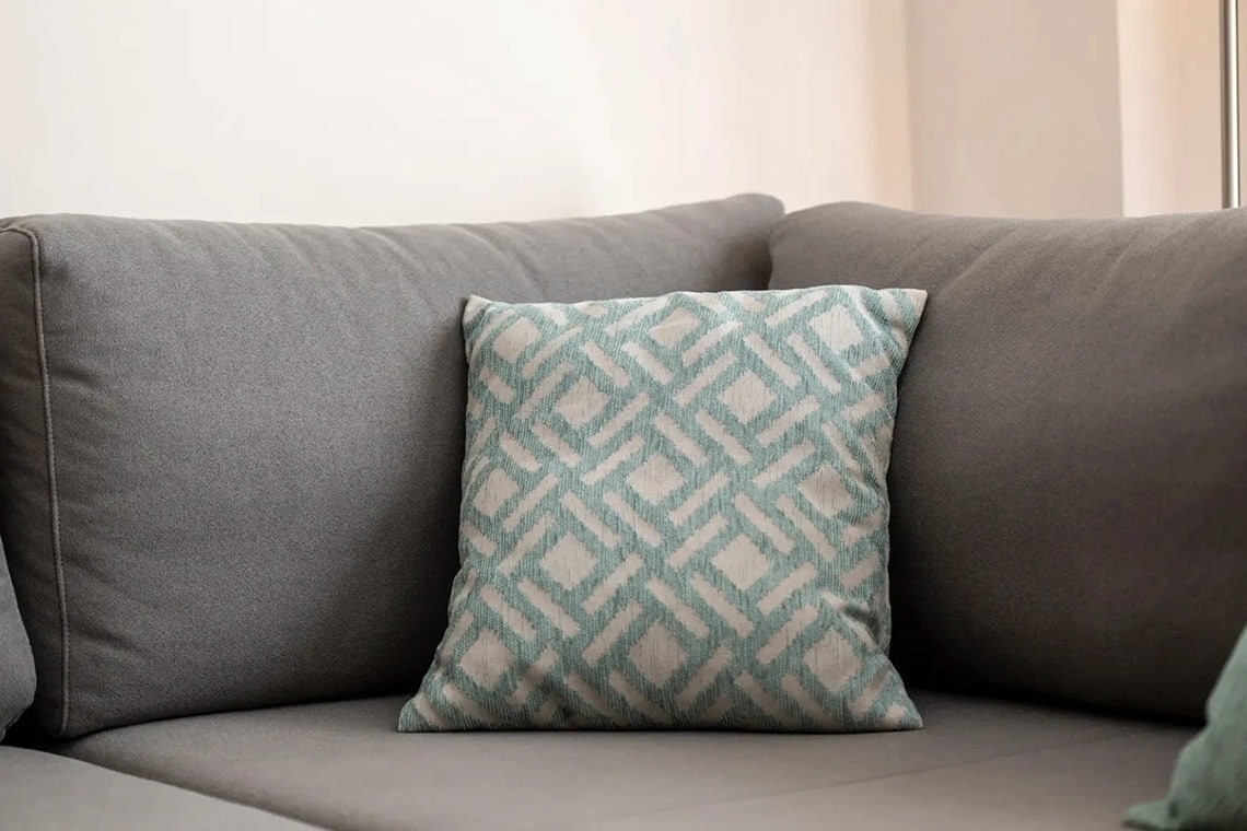 una almohada con un patrón geométrico está sentada en un sofá gris
