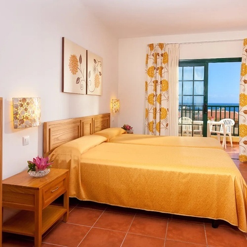 a bedroom with two beds and a balcony overlooking the ocean