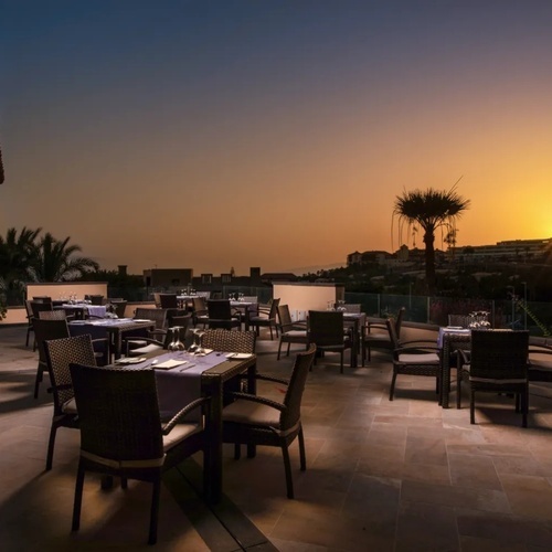 una terraza con mesas y sillas al atardecer