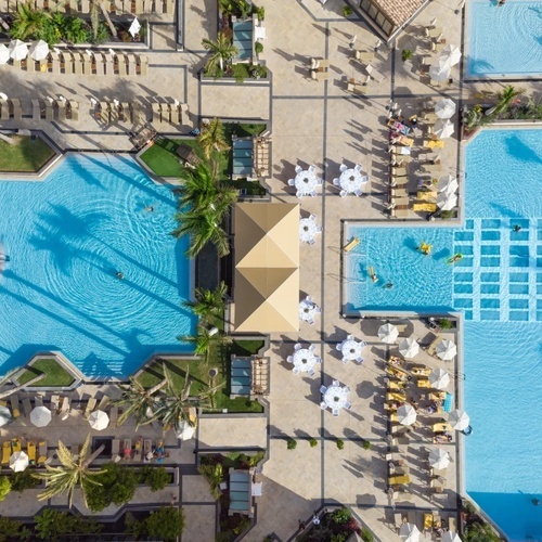 una vista aérea de una gran piscina con mesas y sombrillas