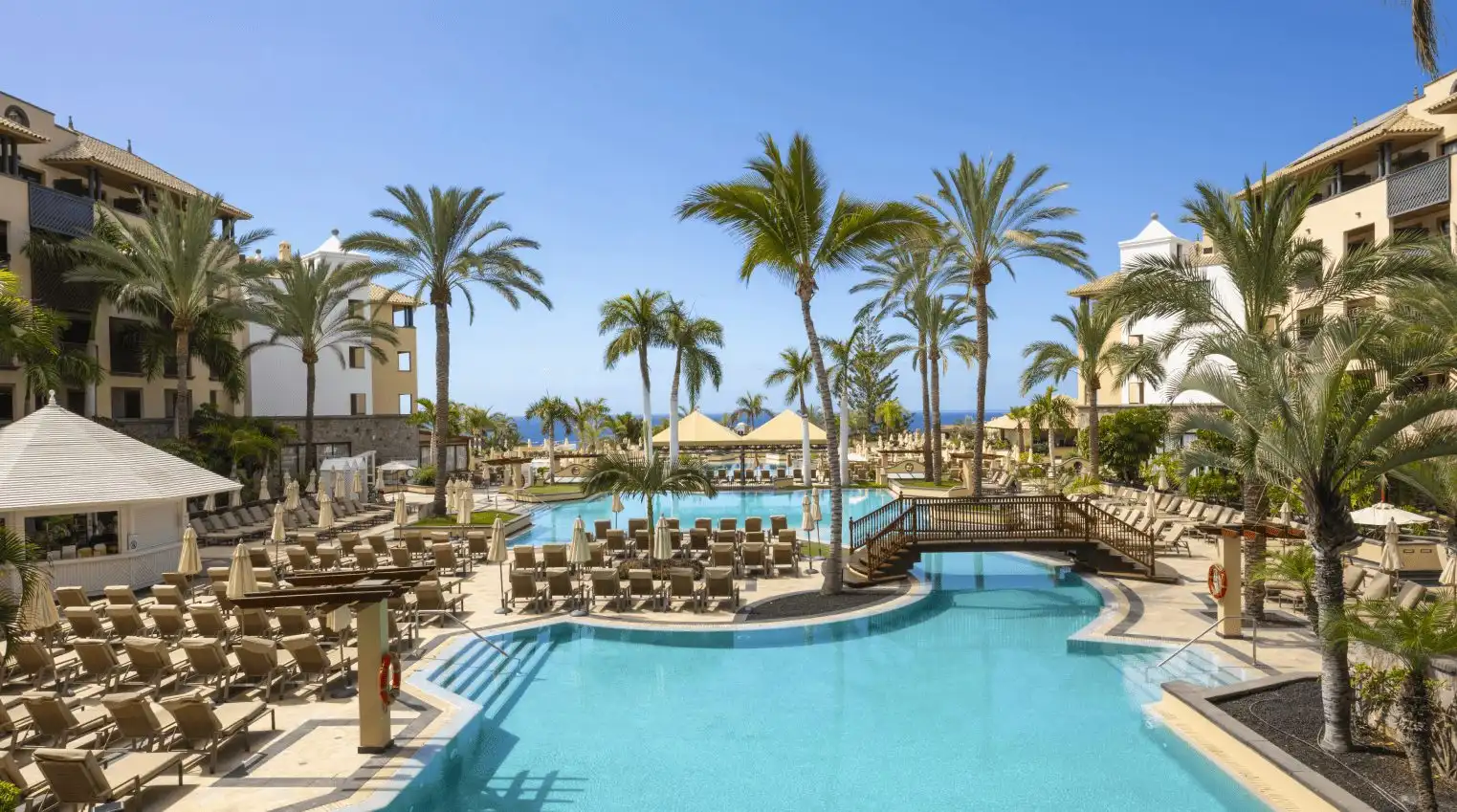 Piscina cristalina y palmeras en GF Gran Costa Adeje, hotel 5 estrellas en Tenerife.