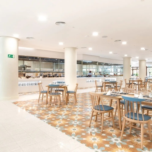 un restaurante con muchas mesas y sillas y una señal de salida verde