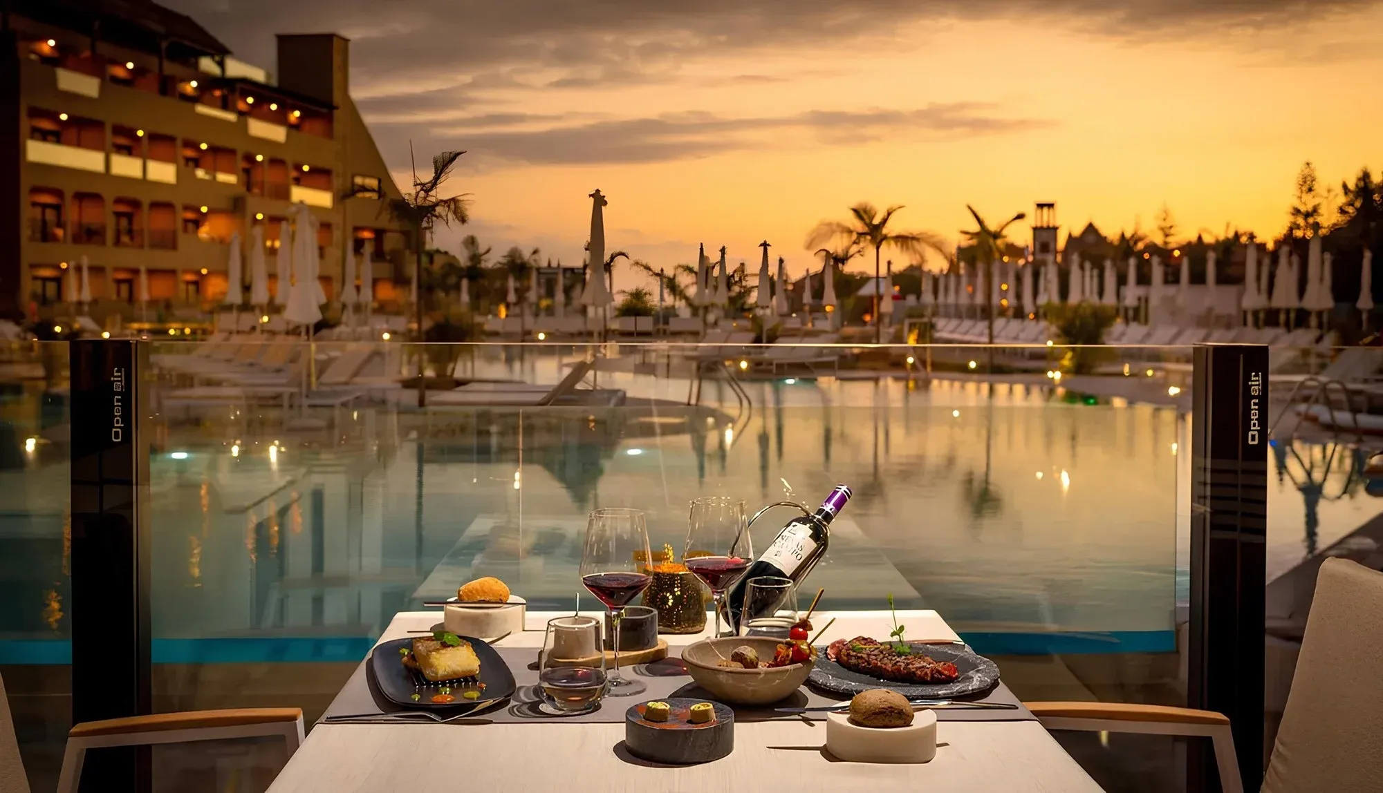 Romantic GF: Corporativa dinner by the pool at sunset with a bottle of wine.