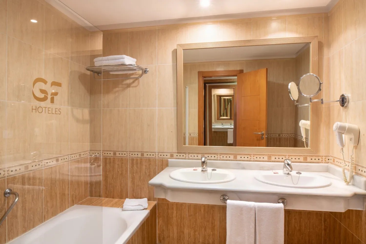 un baño con dos lavabos y la palabra hoteles en la pared