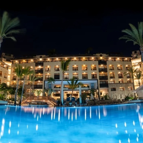 un gran edificio con palmeras y una piscina al frente