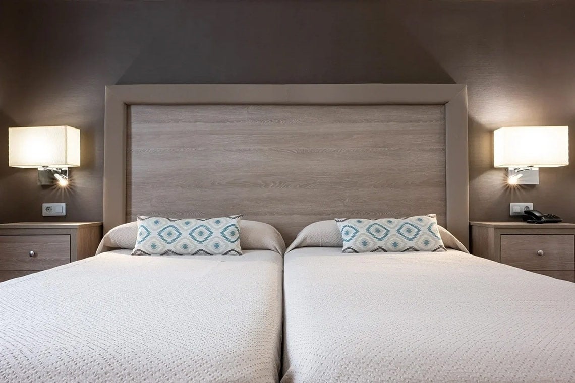 una habitación con dos camas y dos mesitas de noche