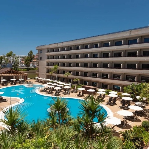 a large hotel with a large pool surrounded by chairs and umbrellas