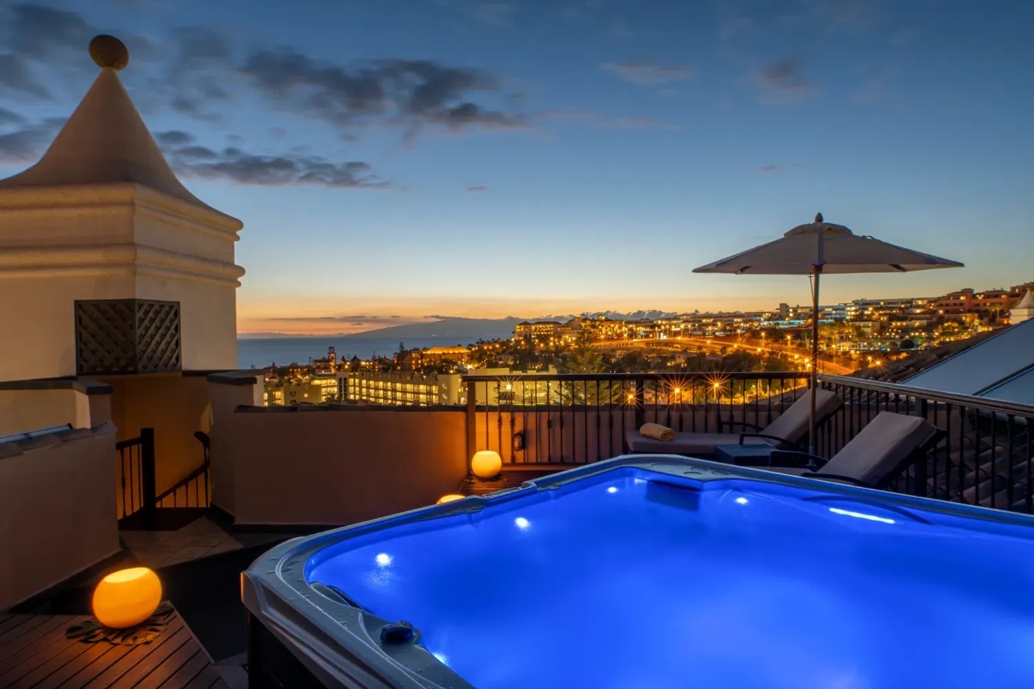 una bañera de hidromasaje en una terraza con una vista de la ciudad al atardecer