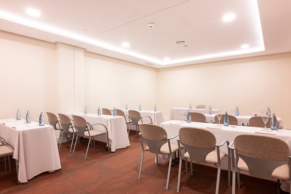 Salón de eventos corporativos con mesas y sillas listas para conferencias.