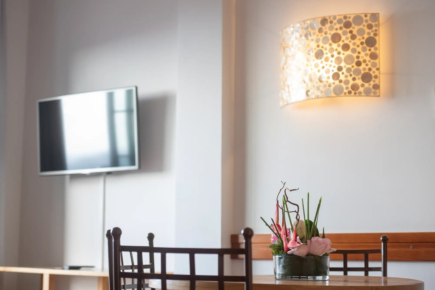 una mesa con flores y un televisor en la pared