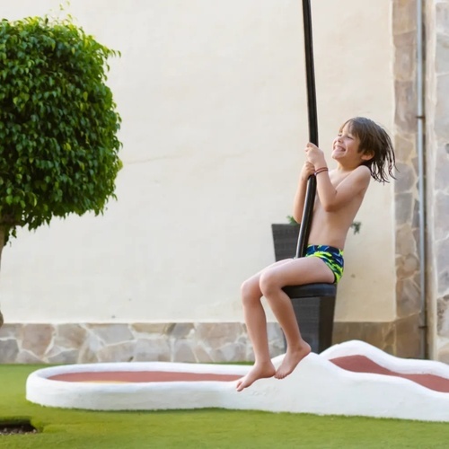 a young boy is sitting on a rope swing