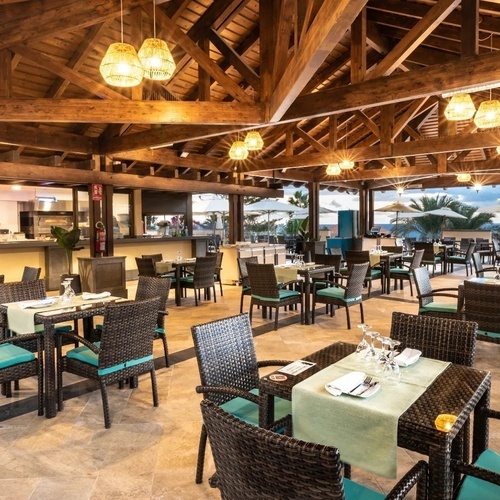 un restaurante con mesas y sillas de mimbre y techo de madera