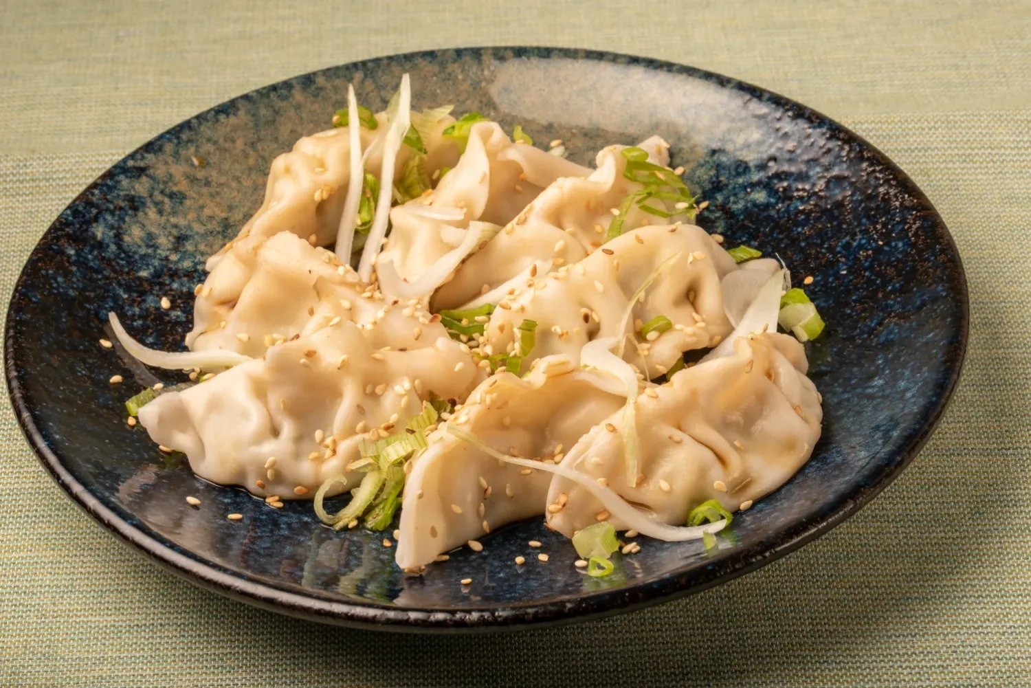 a plate of dumplings with sesame seeds and green onions