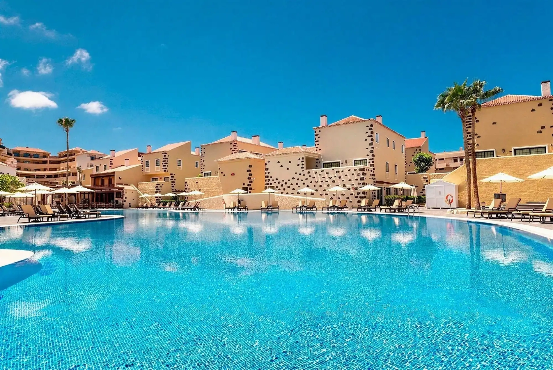 Gran piscina de hotel con tumbonas y palmeras. Reserva anticipada | GF Isabel.