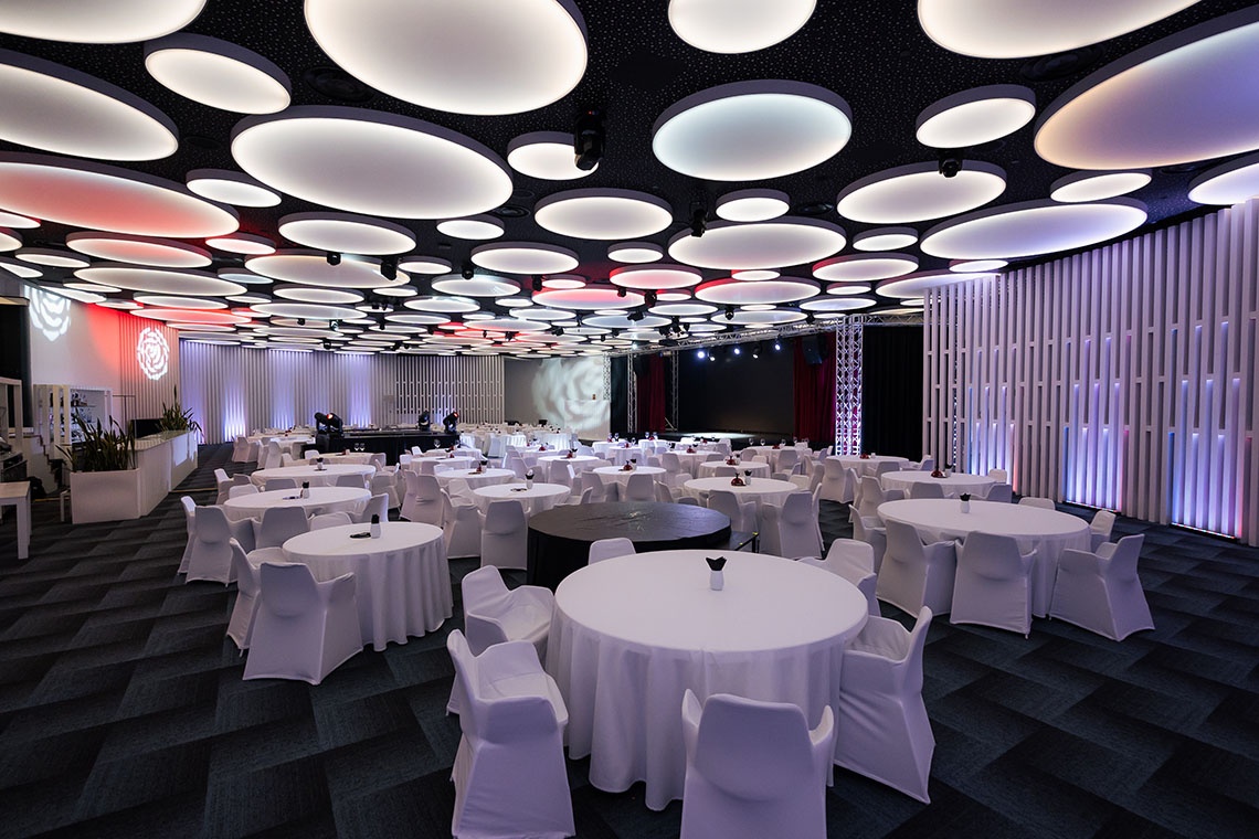 Salón para eventos corporativos con iluminación LED moderna y techo circular.
