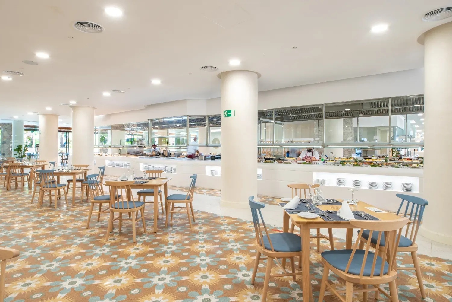 a restaurant with tables and chairs and a green exit sign