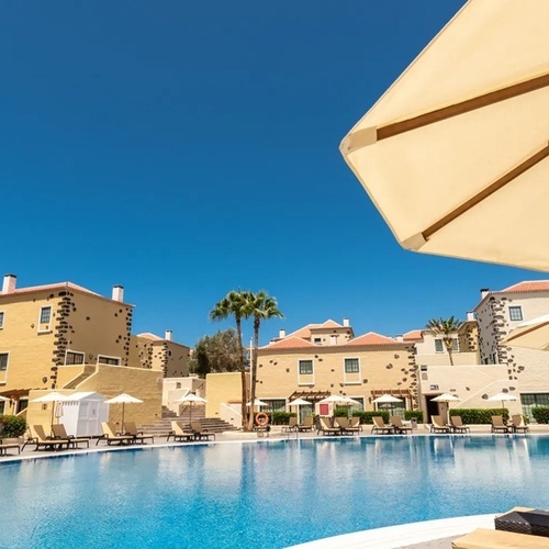 a large swimming pool surrounded by chairs and umbrellas