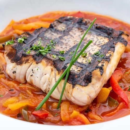 un primer plano de un plato de comida con pescado y verduras