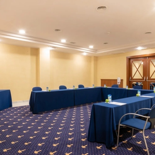 una sala de conferencias con mesas y sillas en forma de u