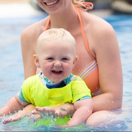 a woman is holding a baby in a swimming pool