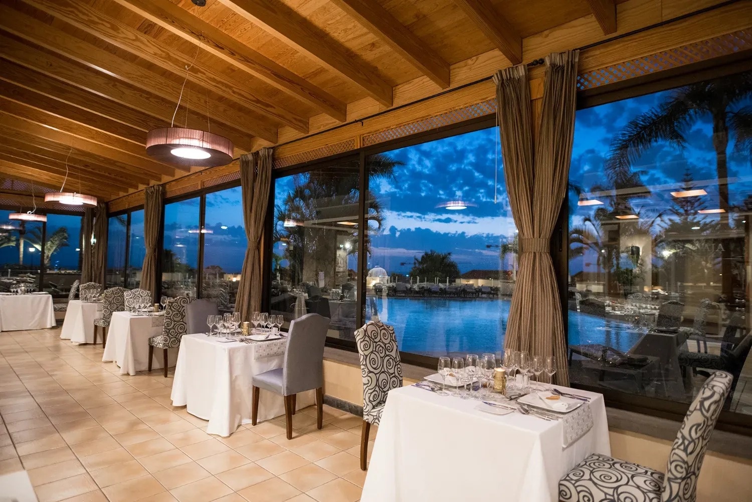 un restaurante con mesas y sillas y una piscina al fondo