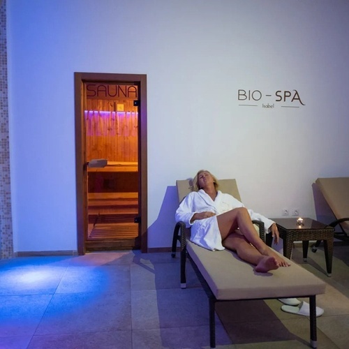 a woman sits on a lounge chair in front of a sauna