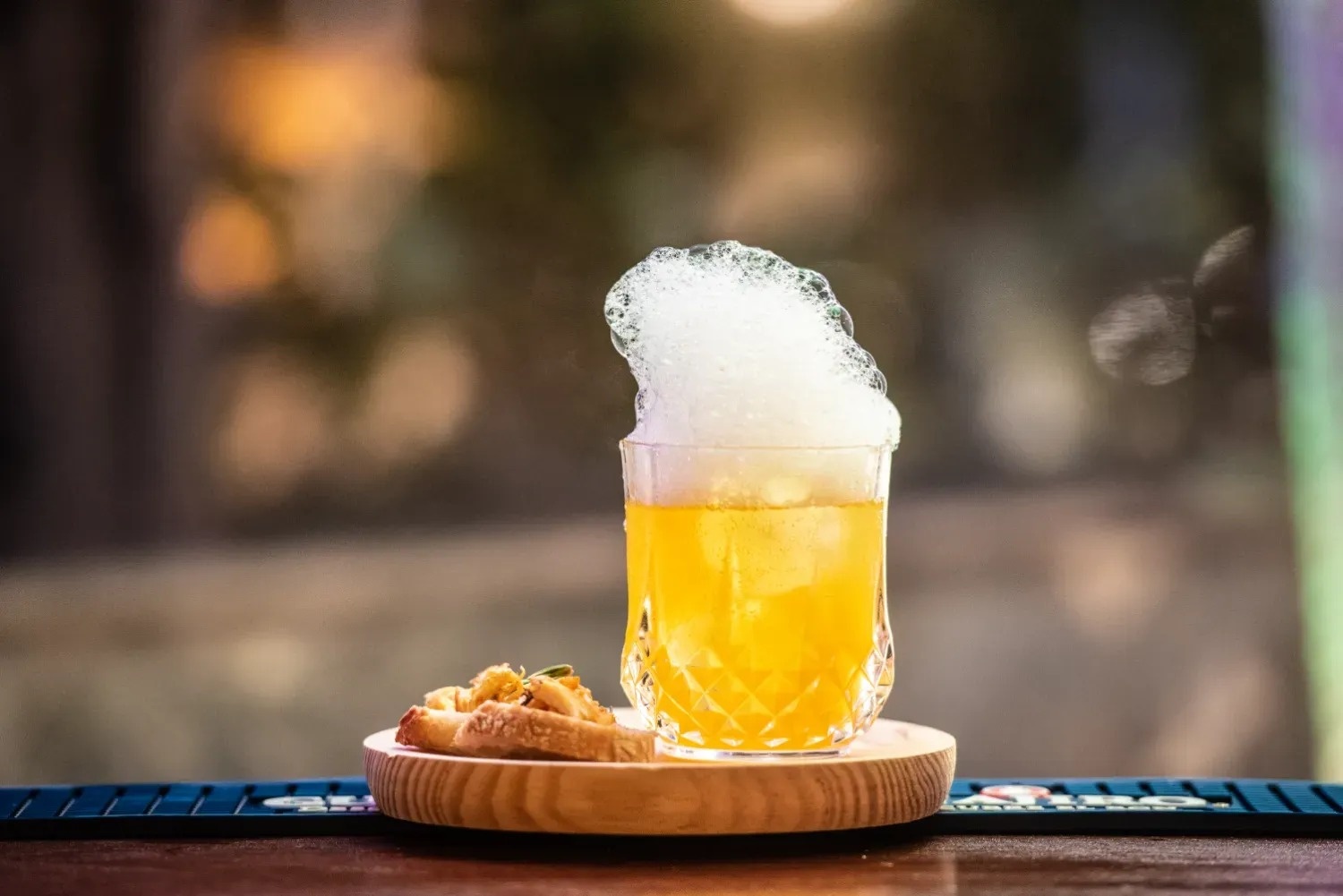 un vaso de cerveza está sobre una bandeja de madera junto a un trozo de pan