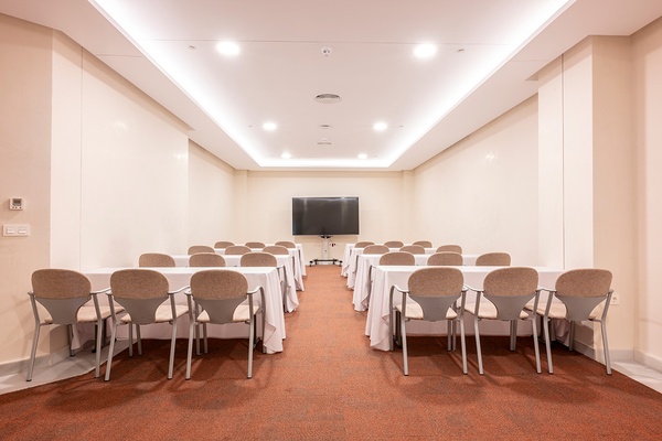 Sala de conferencias en GF: Victoria con mesas azules y sillas, vista al exterior.