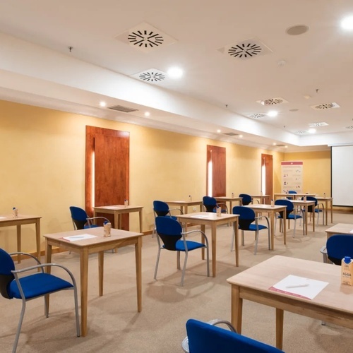 a classroom with tables and chairs and a projector screen