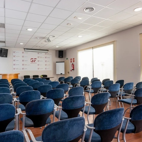 una sala de conferencias con sillas azules y un cartel que dice gf