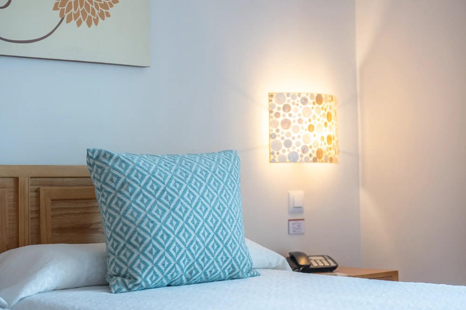 una cama con una almohada azul y una lámpara en la pared