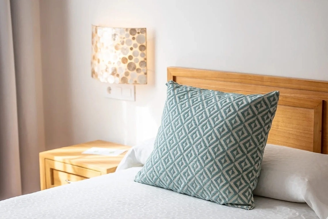 una cama con una almohada y una lámpara en la pared