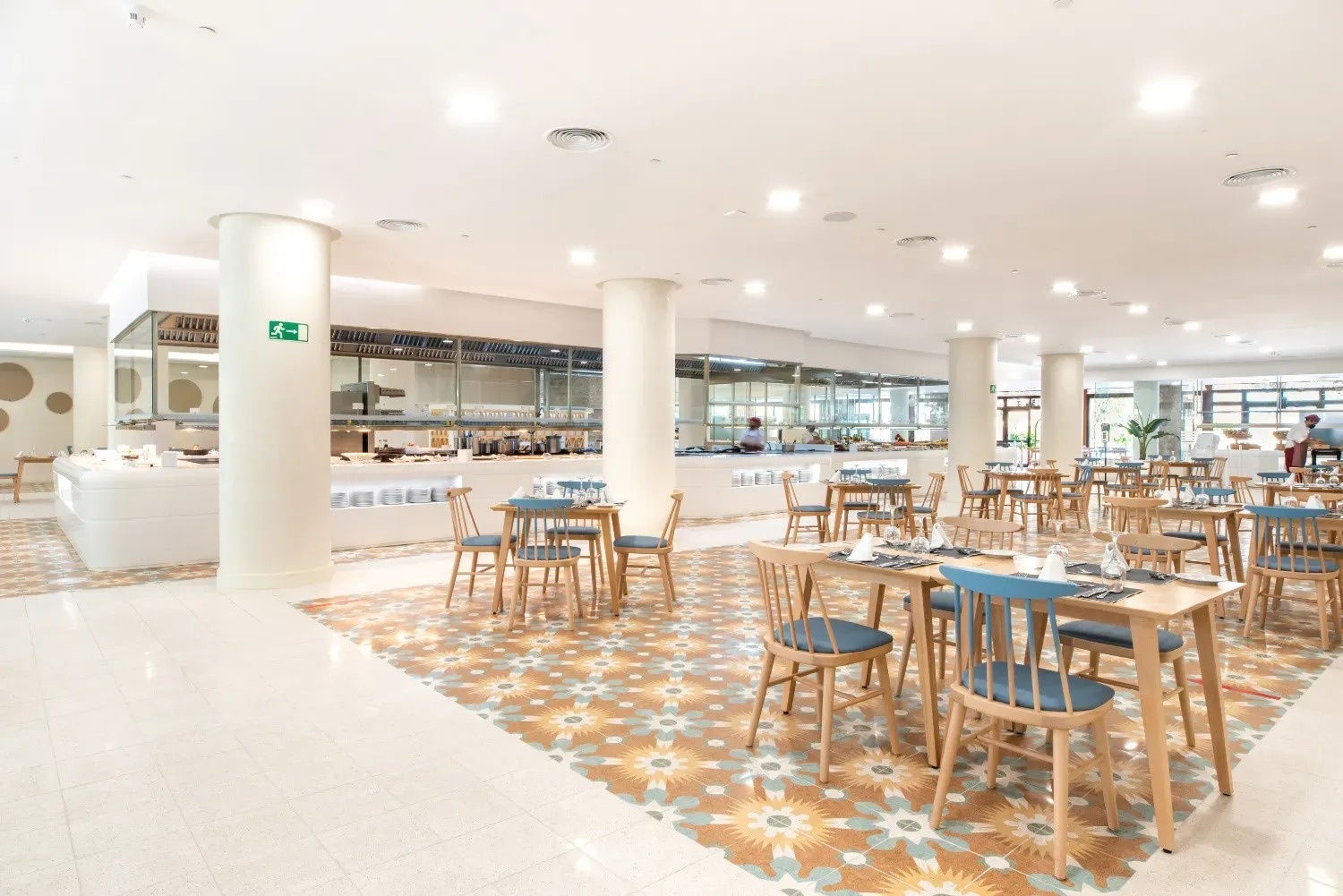 a restaurant with tables and chairs and a green exit sign