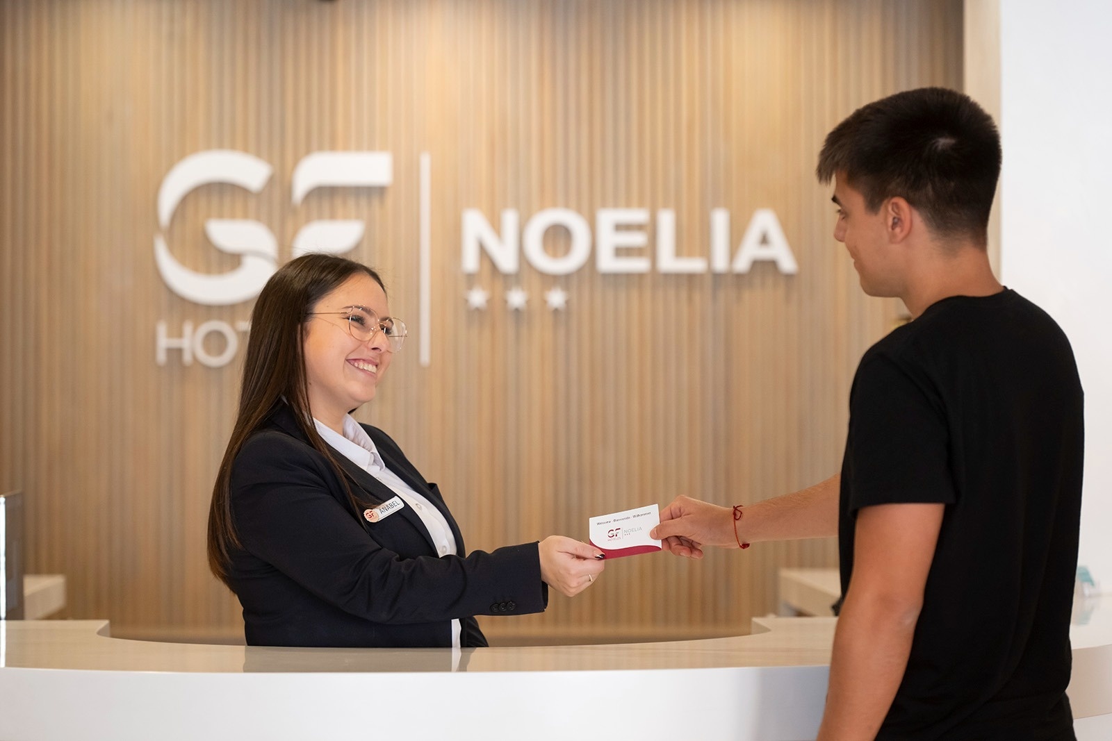 un hombre recibe una tarjeta de visita de una mujer en la recepción del hotel noelia