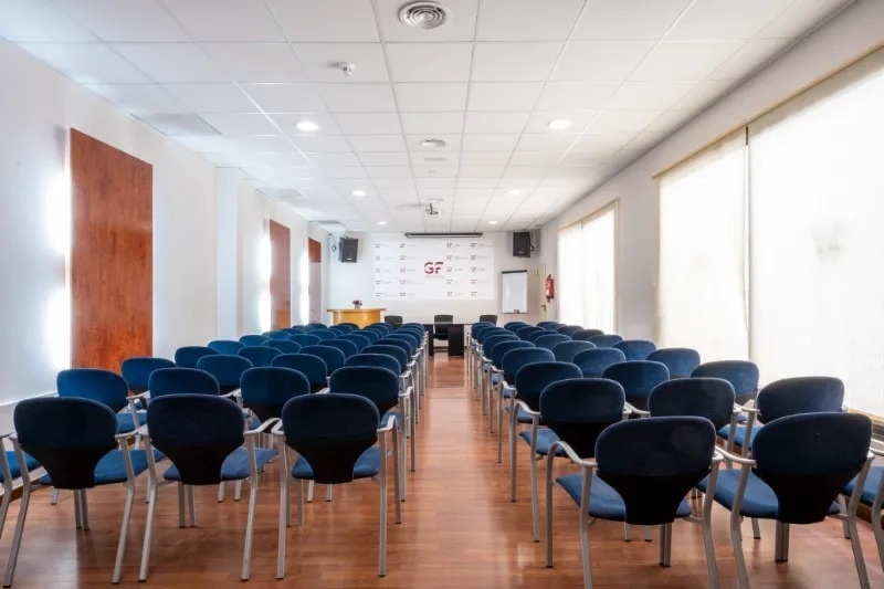 una sala de conferencias con mesas y sillas y un cartel que dice hoteles gf