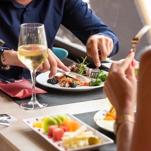 a man and a woman are sitting at a table with a plate of food and a glass of wine