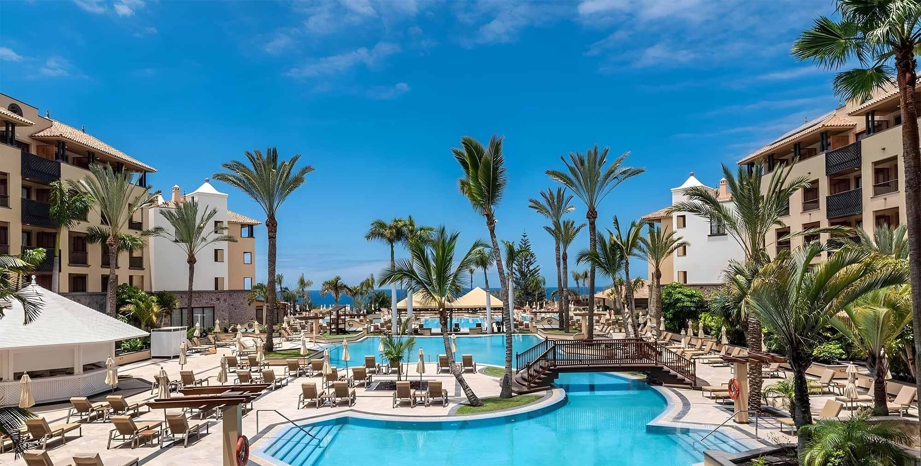 a large swimming pool surrounded by palm trees and chairs