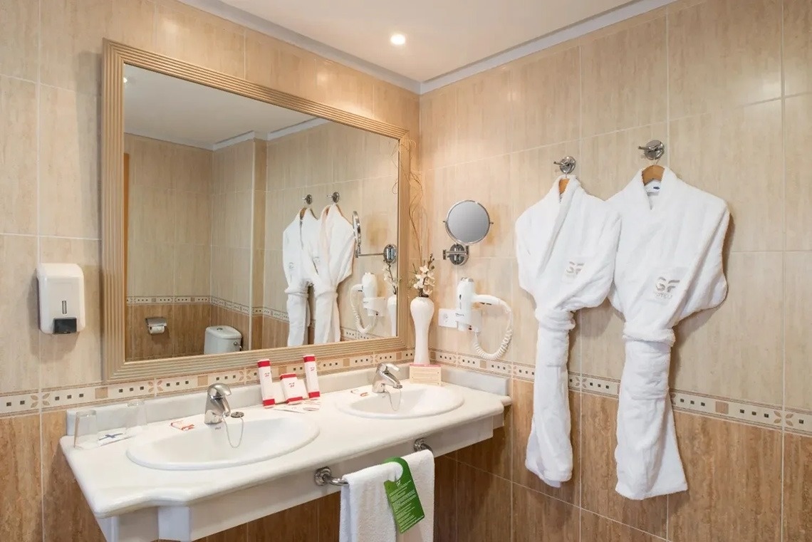 un baño con dos albornoz y un espejo