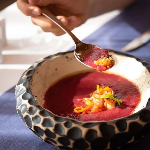 una persona está comiendo una sopa de un tazón con una cuchara