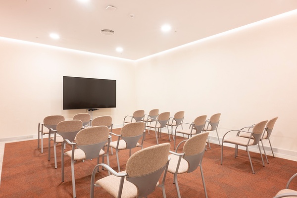 Sala de conferencias moderna en GF: Victoria con mesa en U, sillas y pantalla.