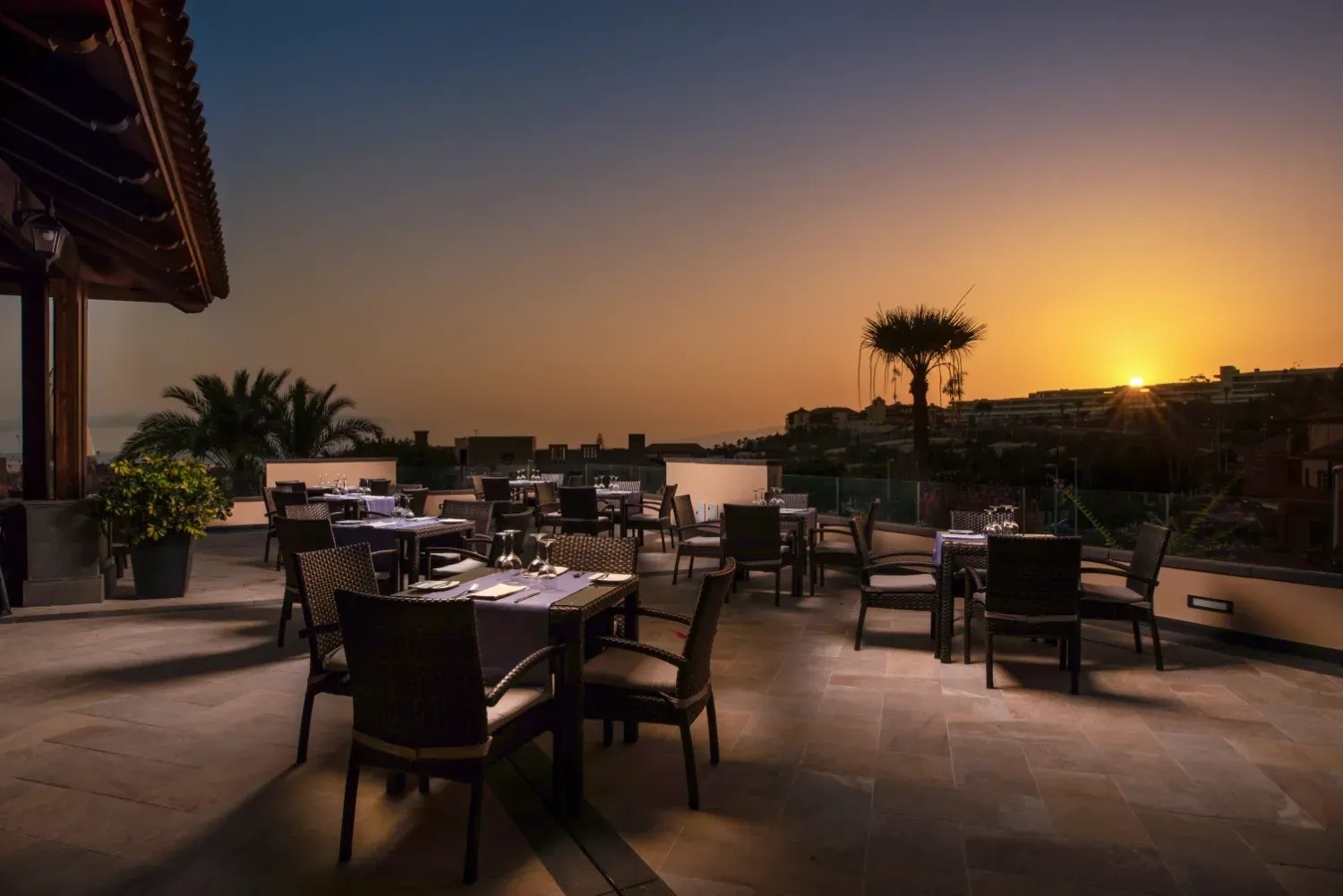 a restaurant with tables and chairs set up at sunset