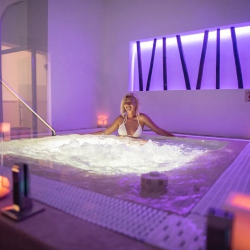a woman sits in a hot tub with the word vivim on the wall behind her