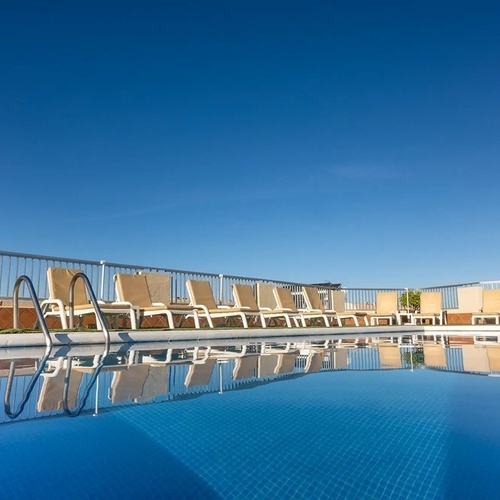 una piscina llena de sillas y escaleras en un día soleado