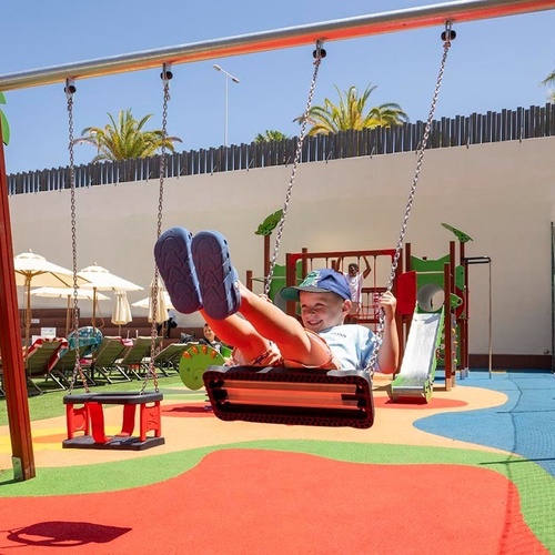 a boy in a blue hat is swinging on a swing set