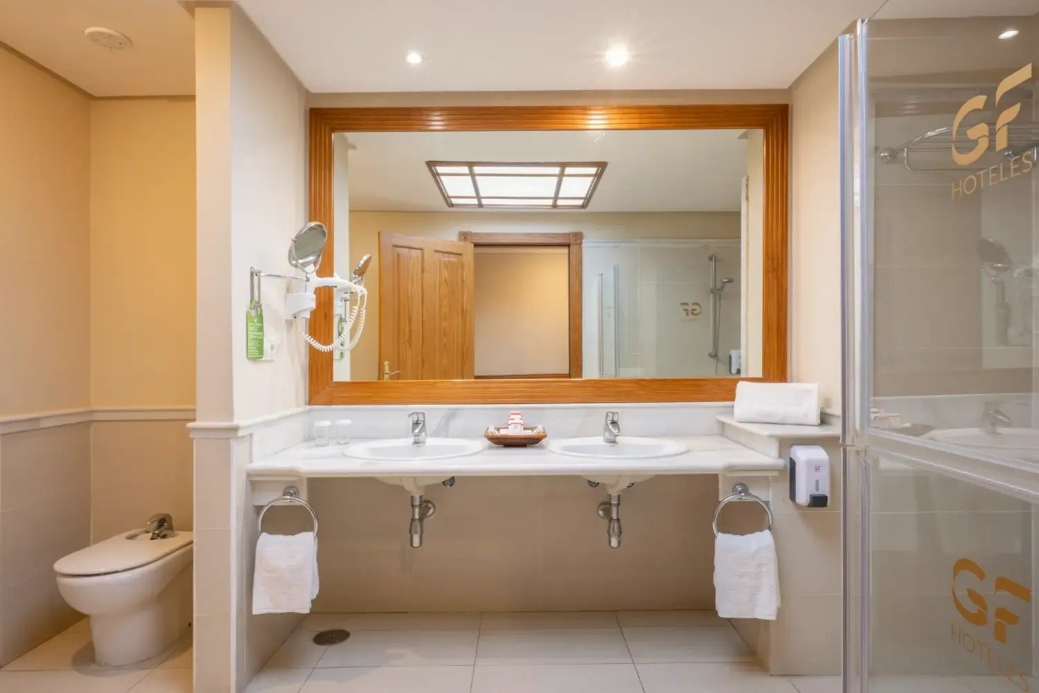 un baño con dos lavabos y un inodoro y la palabra hoteles en la pared